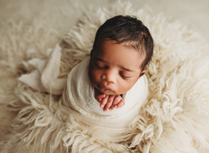 Newborn baby boy sleeping in mother’s arms during NYC photo session