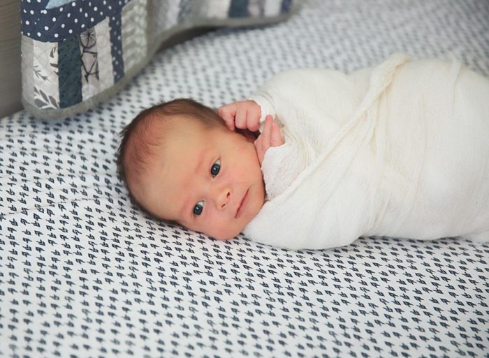 Parents and newborn photographed together in their NYC apartment bedroom