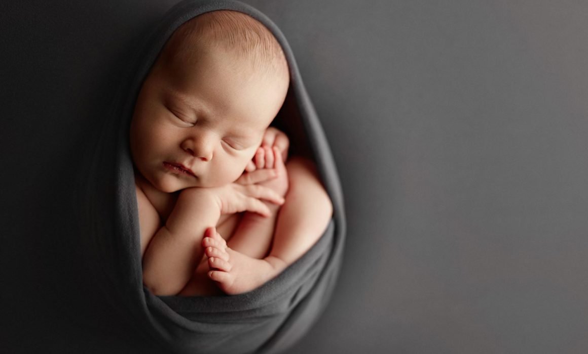 posed newborn photographer wrapped in a gray wrap 2 week old baby in New York session.