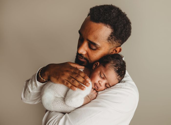ather holding newborn baby boy in a New York City apartment