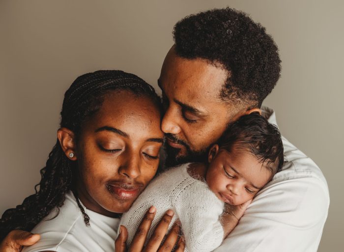 Newborn baby boy curled up on bed during Manhattan in-home photo session
